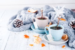 Traditional winter beverage tea with mint and tangerine. Christmas drink. Gray background with knitted scarf