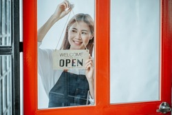 Back view glass door small business owner holding a sign to open a shop