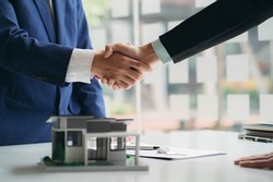 Real estate professionals and clients discussing home purchases, insurance or real estate loans. Home sales agents sit at the office with new homebuyers in the office
