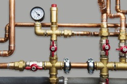 Heating system's cooper pipes with ball valves and manometer on a grey wall