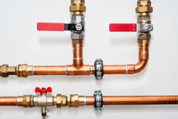 Copper pipes and valves on a white wall. Close up.