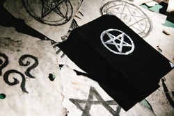 Occult grimoire, magic book laying on table with occult symbols, candles, pentagrams, fortune telling, ritual, altar, spiritism, secret knowledge, scull 