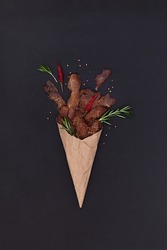 Jerky snacks, red papper and rosemary in craft paper bag on black background. Dried and spiced meat for beer.