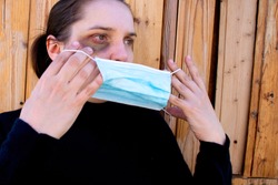 A woman is trying to hide traces of domestic violence by wearing a medical mask. The concept of rising domestic violence during quarantine isolation COVID-19.