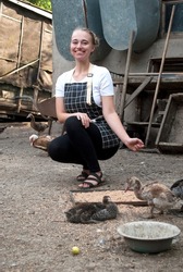Young woman farmer feeds ducks. Household yard. Indo-women.