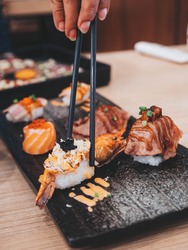 Shrimp sushi nigiri on a black plate with black chopsticks. Closeup of Japanese sushi set nigiri and sushi rolls.Eating japanese food on black slate dishes at restaurant