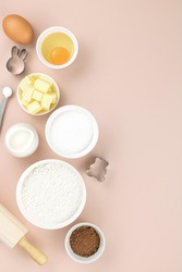 Baking ingredients and tools - flour, sugar, butter, eggs, cocoa, milk, baking powder, rolling pin, whisk, cookie cutters. Top view, copy space. Ingredients for cake, cookies, muffins.