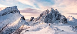 Panorama of Mountaineer standing on top of snowy mountain range at Senja, Norway