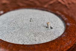 Used cigarette filter in heap sand on ashtray bucket