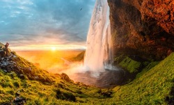 Panorama of spectacular Seljalandsfoss waterfall flowing and midnight sunset shining in summer at South of Iceland