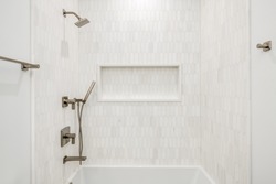 Contemporary Bathtub Enclosure with Gold Fixtures. White and gray tiled bathtub surround with gold fixtures and white tub.