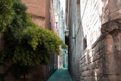Narrow passageway between old stone brick building walls. View of an alley