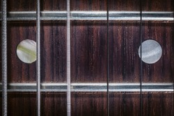 A close up off the 12th fret of an electric guitar, with the D string in a motion blur.