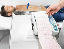 Patient getting heart rate monitored with electrocardiogram equipment. Cardiogram test, close-up of ECG report
