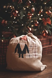 Santa Claus bag full of gifts and Christmas tree on background