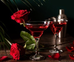 Delicious refreshing beverage drink red cocktail with red rose and petals on wooden table. Romantic, Valentines day concept