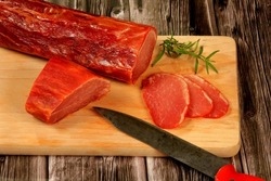 Spanish meat delicacy from pork dry-cured carbonade Lomo Curado on wooden board. Iberian pork slices. cured pork tenderloin or lomo embuchado