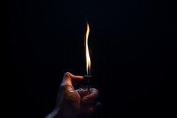 Hand with lighter igniting sparks on dark background