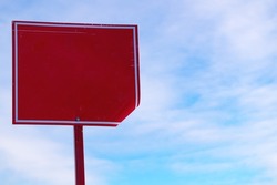 An old forbidding sign without an inscription on a background of blue sky and white clouds.Metal support with a red rectangle.A crumpled and bent forbidding sign in daylight.