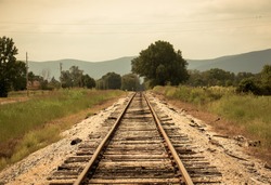 An old rail road track with mountains in background