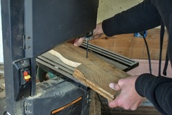 A person cutting a board using a band saw- Arts and Crafts- DIY wood working projects- cutting a piece of wood in a wood shop- making a wooden craft using a bandsaw- cutting along a line