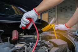 The hands of technicians use charging cables for batteries for cars. The concept of attaching batteries to start a broken car.