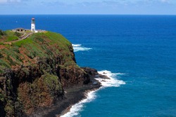 White Lighthouse set atop a cliff with a brilliant blue ocean in the background in Kauai, Hawaii, USA. 