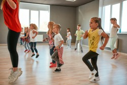 Group of little boys and girls dancing while having choreography class in the dance studio. Female dance teacher and children dancing. Contemp dance. Hip hop. Kids and sport. Full length