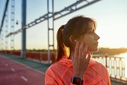 Close up millennial gen z active sporty woman in modern earphones gadget workout train outdoors listen to music. Young fit female runner wear headphone jog run in street. Healthy life, sport concept.