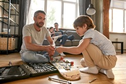 Caring Caucasian father teach teen son use deal with tools repair skateboard at home together. Young dad and small teenage boy child fix sport board with toolset equipment. Fatherhood, hobby concept.