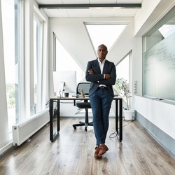 Serious black male businessman with crossed arms looking at camera in office. Adult company boss wearing formal wear. Concept of modern successful man. Idea of business leadership and management