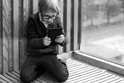 boy 6 years old plays with enthusiasm look into the tablet. monochrome image