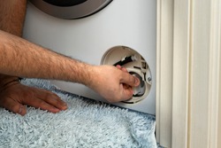 the master opens the filter of the washing machine to remove the blockage. Problem with Laundry.