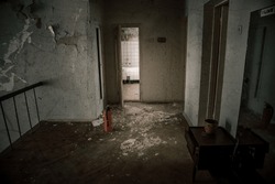 An old room with shabby walls in an abandoned house. Old broken doors. Dirty floor. The atmosphere of an abandoned house.