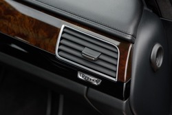 Car air conditioner close up. Automotive climate control. Air flow inside the car. Interior element of a modern premium car. Wooden components and inserts in the interior of a business class car.