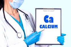 CALCIUM Ca text is written on a tablet which the doctor holds in a medical gown and gloves. Medical concept.