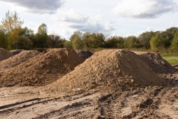 Mountain of sand at a construction site. Foundation material. Soil prepared to strengthen the soil. Earthen heap. Fine sand to create a concrete mortar.