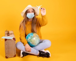 A tourist girl with a medical mask, outbreak of coronavirus COVID-19. Concept of canceled trips. A tourist cannot leave due to a pandemic.