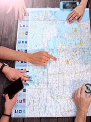 hands of group of friends looking for a place to travel on a map