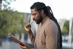African American man, with dreadlocks, and spectacles, reading a book at sunset