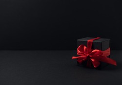 Black gift boxes with red ribbon on black background with copy space for text. The Concept Of Valentine's Day.