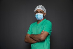 Portrait of a male nurse standing with arms folded isolated on a black background. Asian Nurse looking at camera. Male nurse with protective face mask against corona virus epidemic COVID-19
