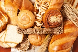 Culinary background with bread,buns,drying bagels,wheat ears in a wicker basket, top view