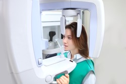 The girl in the X-ray room makes a panoramic picture of her teeth. Disease prevention and dental treatment. X-ray equipment. Panoramic image of teeth. Modern dentistry and medicine. Copy space.