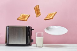 Toasts flew out of toaster. Near glass of milk. Levitation food. Delicious morning breakfast on pink background.
