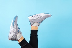 Male legs wearing sneakers over blue background. Sport shoes for training in the gym. Man in running sneakers near color wall.