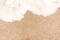 Coarse sand on beach with sea foam