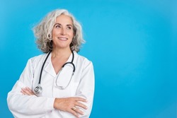 Mature female doctor looking up with the arms crossed