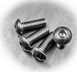 DIN 7380 screw bolt metallic iron close up macro on stainless steel background