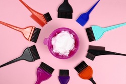 Hair coloring tools - plastic bowl with hair dye and brushes on pink background